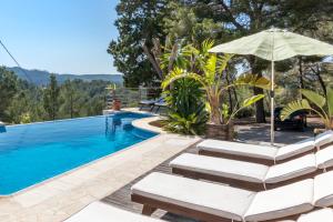 a swimming pool with chairs and an umbrella at Villa Cala Xuclar in Portinatx
