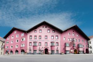 ein großes rosafarbenes Gebäude mit schwarzem Dach in der Unterkunft Hotel Krone in Matrei am Brenner