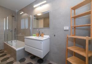 a bathroom with a sink and a shower and a mirror at Yalarent Europe apartments- Luxury big apartmens with lake view in Tiberias
