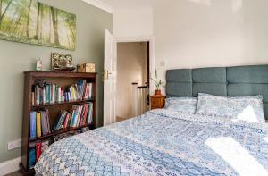a bedroom with a bed and a book shelf with books at Lovely house (Ealing, London) in London