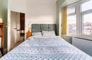 a bedroom with a large bed and two windows at Lovely house (Ealing, London) in London