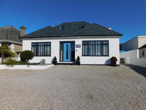 a white house with a blue door on a gravel driveway at Haven Lodge Newquay in Newquay