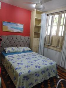 um quarto com uma cama e uma parede vermelha em Copacabana Posto 2 no Rio de Janeiro