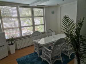 a dining room with a table and chairs and windows at Apartment holidays and partys with a pool in Tuzla