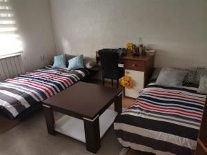 a room with two beds and a table and a desk at Apartment holidays and partys with a pool in Tuzla