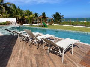 a swimming pool with lounge chairs and a playground at Itacimirim Beira Mar in Itacimirim