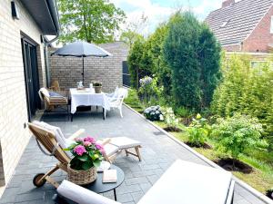 eine Terrasse mit einem Tisch, Stühlen und einem Sonnenschirm in der Unterkunft Freya Blue Ferienhaus in Weener