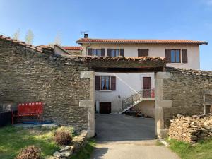 uma casa de pedra com um banco vermelho em frente em Gite cosy 25 min Lyon Vienne St Etienne em Longes