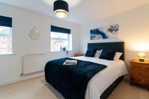 a bedroom with a large bed and two windows at Pride Park House in Derby