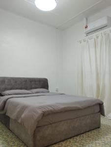 a bed in a bedroom with a white wall at Batu Pahat Taman Banang Homestay in Batu Pahat