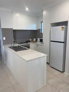 een witte keuken met een wastafel en een koelkast bij Stylish 2Bed Close Airport/Shops in Perth