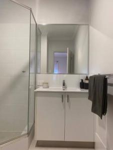 uma casa de banho branca com um lavatório e um chuveiro em Stylish 2Bed Close Airport/Shops em Perth