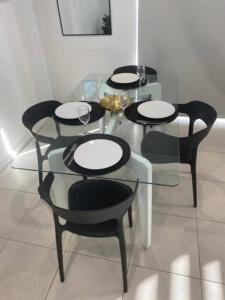 a glass table with four chairs and wine glasses on it at Stylish 2Bed Close Airport/Shops in Perth