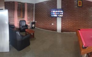 Habitación con 2 sillas y TV en una pared de ladrillo. en Pecas house en Mina Clavero