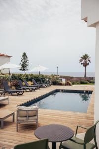 a swimming pool with chairs and a table and a pool at MUTE Hostel Porto Covo in Porto Covo