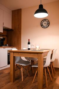 a dining room table with a bottle of wine and a clock at Lena Apartman in Subotica