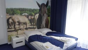 a bedroom with a bed with a horse painting on the wall at Janowski Zakątek in Janów Lubelski