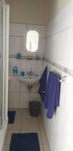 baño con toallas azules y lavabo y ventana en San-Lou Airbnb, en Sunridge Park