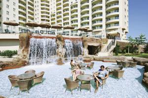 two people sitting at tables in front of a waterfall at Luxery suite GOLDCITY GOLD CITY Alanya in Alanya