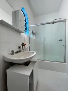 uma casa de banho branca com um lavatório e um chuveiro em Casa Mykonos Represa Avaré em Itaí
