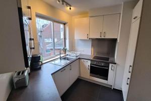 a kitchen with white cabinets and a sink and a window at Chez la Baronne in Brussels