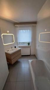La salle de bains est pourvue d'un lavabo, d'une baignoire et d'une fenêtre. dans l'établissement Chez la Baronne, à Bruxelles