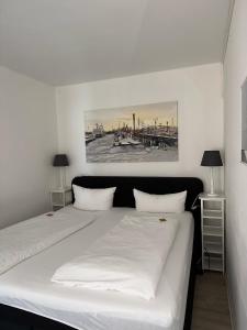 a bedroom with a large white bed with two lamps at Strandhotel in Wyk auf Föhr