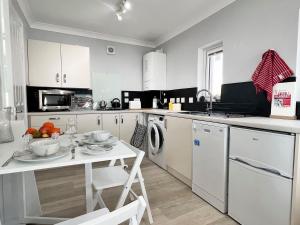 a kitchen with white cabinets and a table with fruit on it at Jayne Cottage in Tarbert