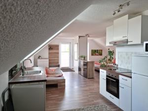 eine Küche mit weißen Schränken, einer Spüle und einer Couch in der Unterkunft Ferienwohnung Braun in Echlishausen