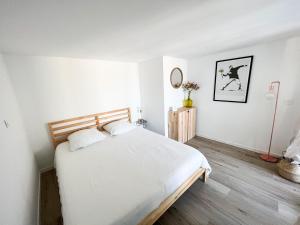1 dormitorio con 1 cama con sábanas blancas y suelo de madera en Dépendance T3 proches des plages en Lattes