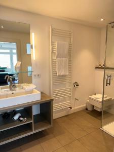 a bathroom with a sink and a shower and a toilet at Strandhotel in Wyk auf Föhr