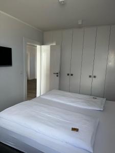 a white bedroom with a large bed with white cabinets at Strandhotel in Wyk auf Föhr