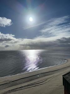 uma praia com o sol refletindo sobre a água em Strandhotel em Wyk auf Föhr