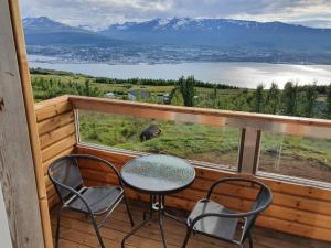 a table and chairs on a balcony with a view of a lake at Akureyri Loghouse in Akureyri