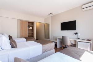 a hotel room with two beds and a desk at Jandaia Turismo Hotel in Santana do Livramento