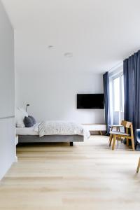 een witte kamer met een bed en een televisie bij Louis & Louise Apartments & Lofts Am Wall I Digital Check In in Bremen
