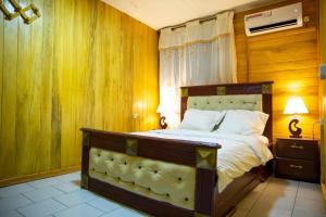 1 dormitorio con 1 cama grande y paredes de madera en La Maison du Bonheur, en Douala