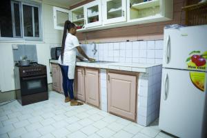 una mujer parada en una cocina preparando comida en La Maison du Bonheur en Duala
