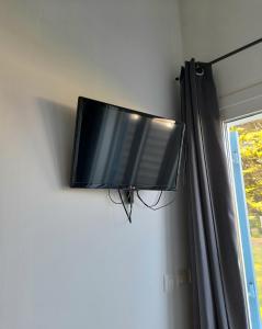 TV de pantalla plana colgada en una pared junto a una ventana en Le Stud' à Saint Pierre d'Oléron ! en Saint-Pierre-dʼOléron