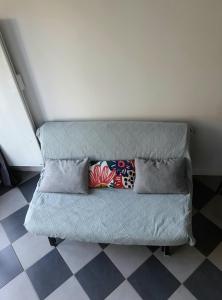 a gray couch with pillows on a checkered floor at Le Stud' à Saint Pierre d'Oléron ! in Saint-Pierre-dʼOléron