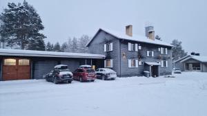 deux voitures garées devant une maison dans la neige dans l'établissement Lägenhet i Kåbdalis nära skidbacke & skoterled, à Kåbdalis