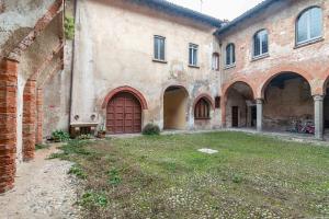 un grand bâtiment en briques avec une porte rouge et une cour dans l'établissement House of Foscolo - Palazzo Cornazzani - by Host4U, à Pavia