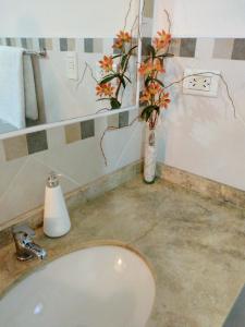 baño con lavabo y jarrón con flores en Lo de Chavela en Salta