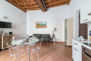 Il dispose d'une cuisine et d'un salon avec une table et des chaises en verre. dans l'établissement House of Foscolo - Palazzo Cornazzani - by Host4U, à Pavia