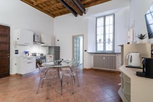 une cuisine avec une table et des chaises dans une pièce dans l'établissement House of Foscolo - Palazzo Cornazzani - by Host4U, à Pavia