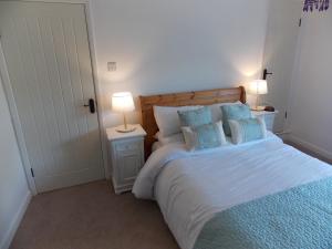a bedroom with a bed with blue pillows and two lamps at Fryers Cottage in Richmond