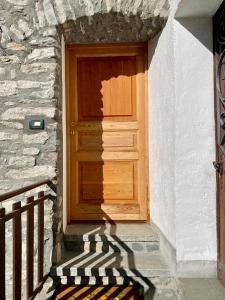 eine Holztür in einem Steingebäude mit einem Schatten in der Unterkunft Appartamento alpino in La Salle