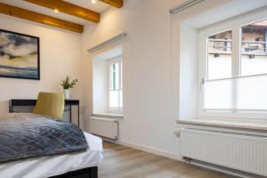 a bedroom with a bed and two windows at Stadtmauer-Apartments - Stilvolle Wohnung mit King Bett direkt an der historischen Stadtmauer in Nördlingen