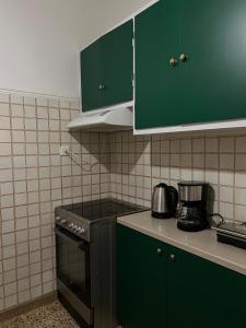 a kitchen with green cabinets and a stove top oven at JR apartments in Athens