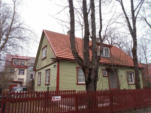 una casa amarilla con techo rojo y valla en Kodu majutus, en Tallin